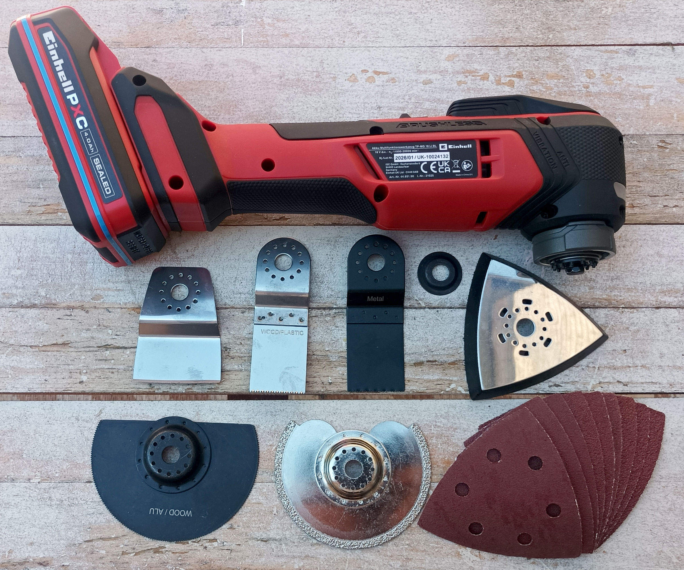 Einhell Multitool with battery, blades and attachments on whitewashed wood