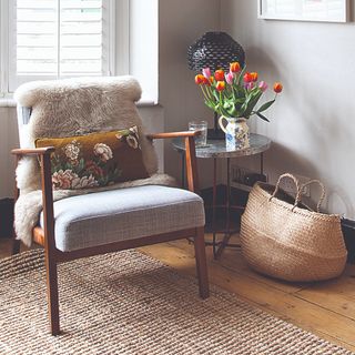 A corner of a living room with an armchair and a vase of tulips
