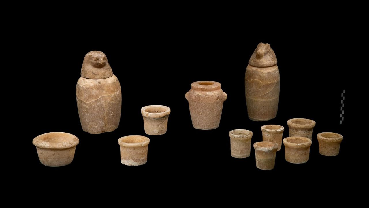 A few of the pottery vessels found in the embalming cache inside the Egyptian tomb. There are 9 little pots, one slightly larger jug-like pot and 2 larger pots that each have a special lid model after an Egyptian god (one looks like the head of a bird/owl, the other like a crocodile head).