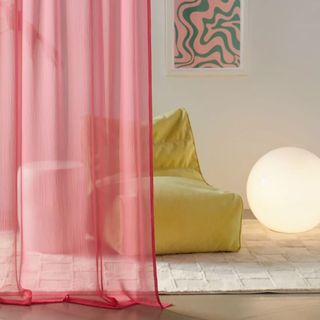 Pink sheer window panel by green couch