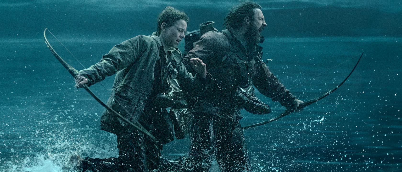 Alfie Williams and Aaron Taylor-Johnson panic as they run through the water in 28 Years Later.