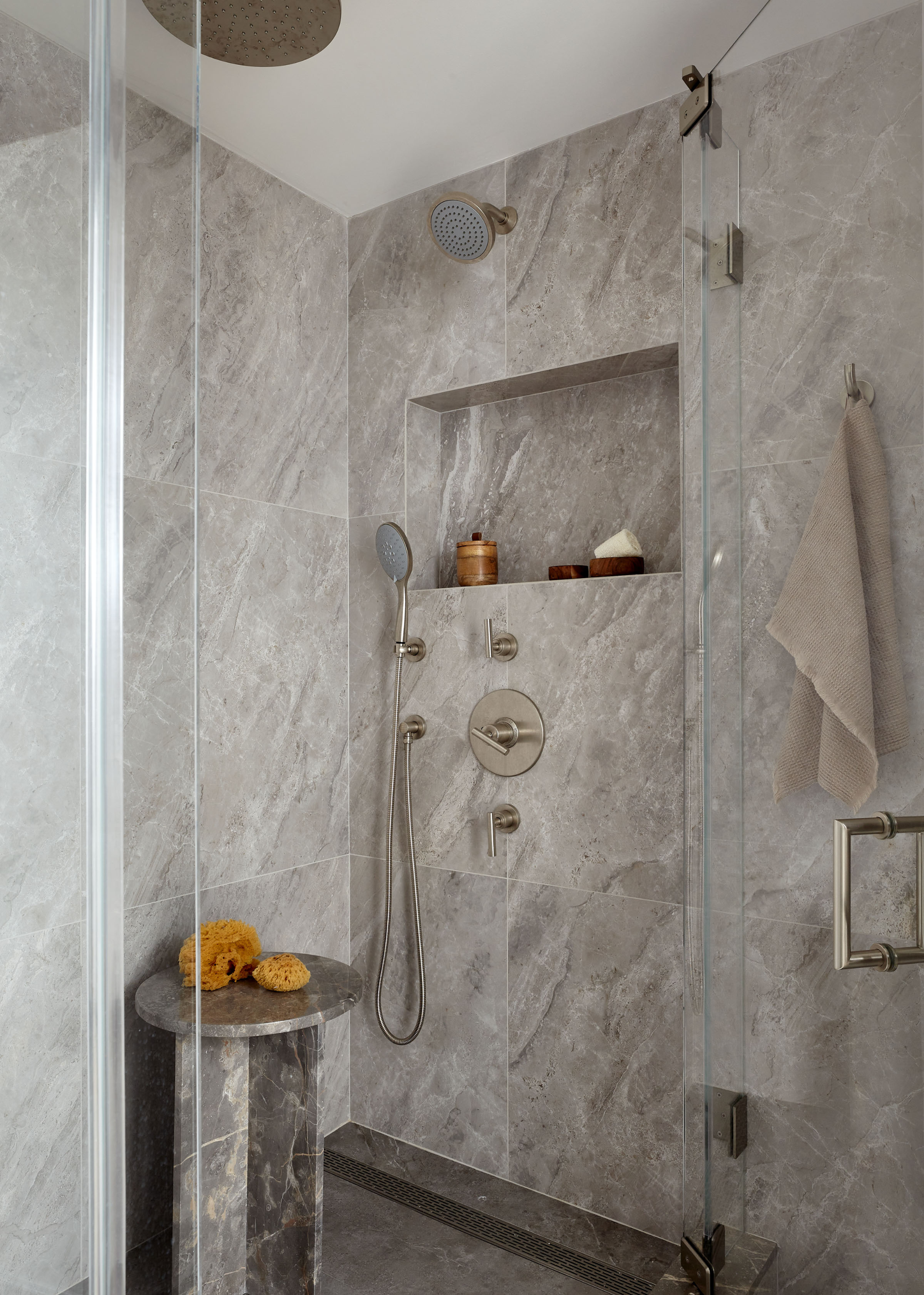 An all grey marble shower with a niche and matching stool