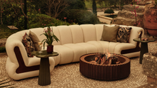 a curved white sofa with green cushions in a garden with a corten steel fire pit in front of it 