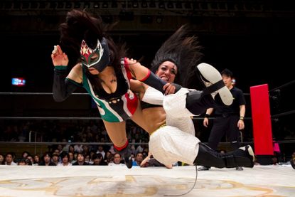 Wrestlers Kris Wolf and Starfire fight during their Stardom professional wrestling show