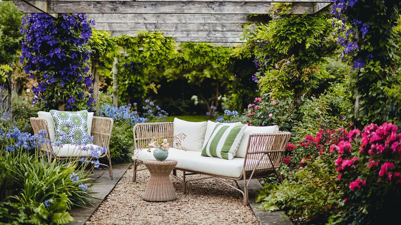 Garden furniture sest under a pergola with climbing flowers