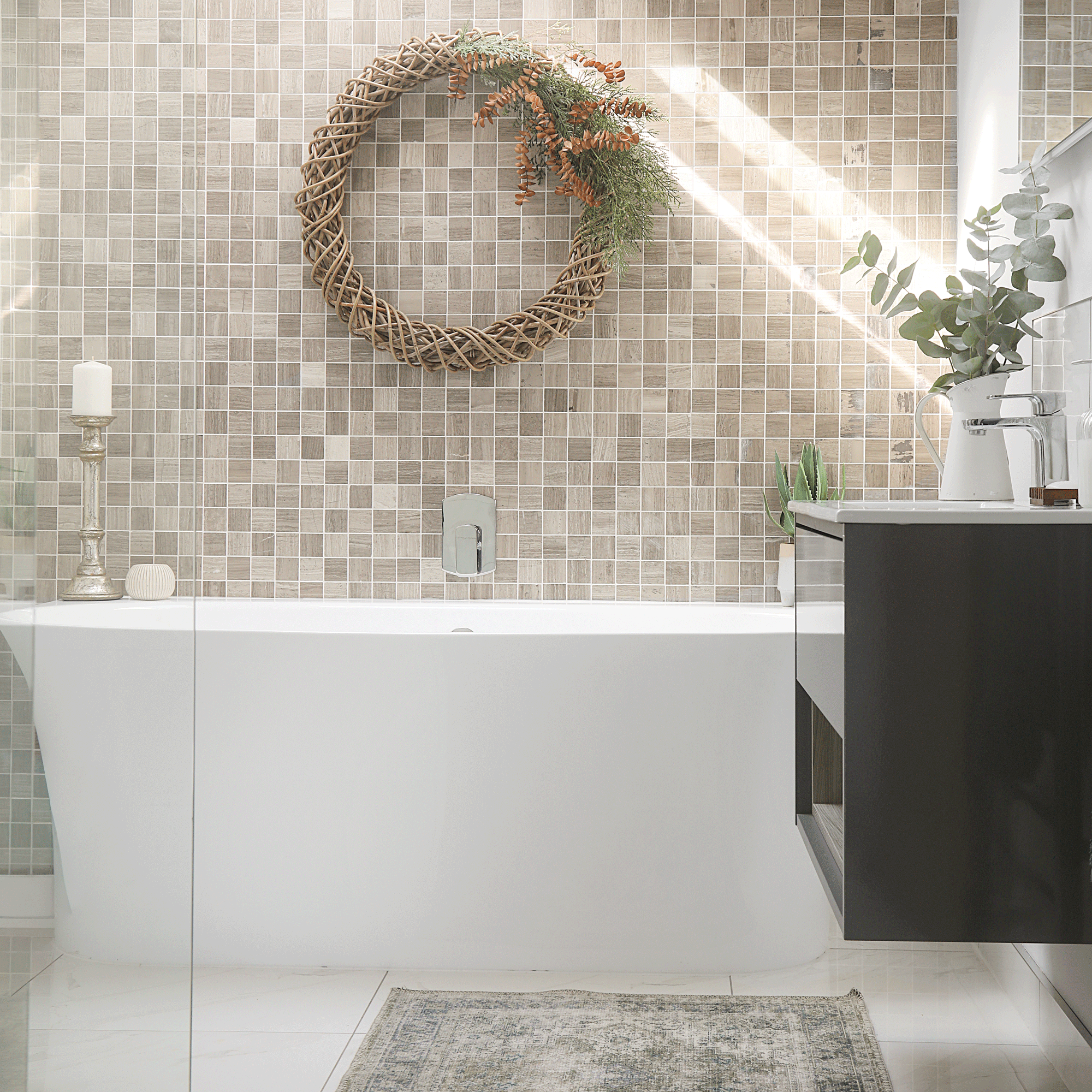 a bathroom with square beige wall tiles and an autumnal wreath above a contemporary bath tub