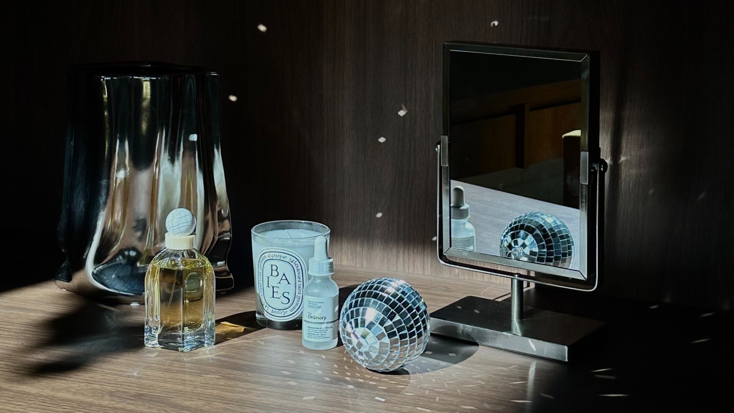 Photo of a candle, mirror, disco ball, and fragrance on a shelf