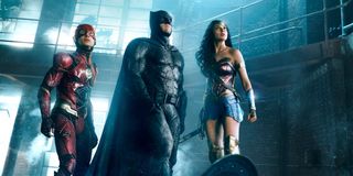 The Flash, Batman and Wonder Woman stand in a warehouse and look up in Justice League