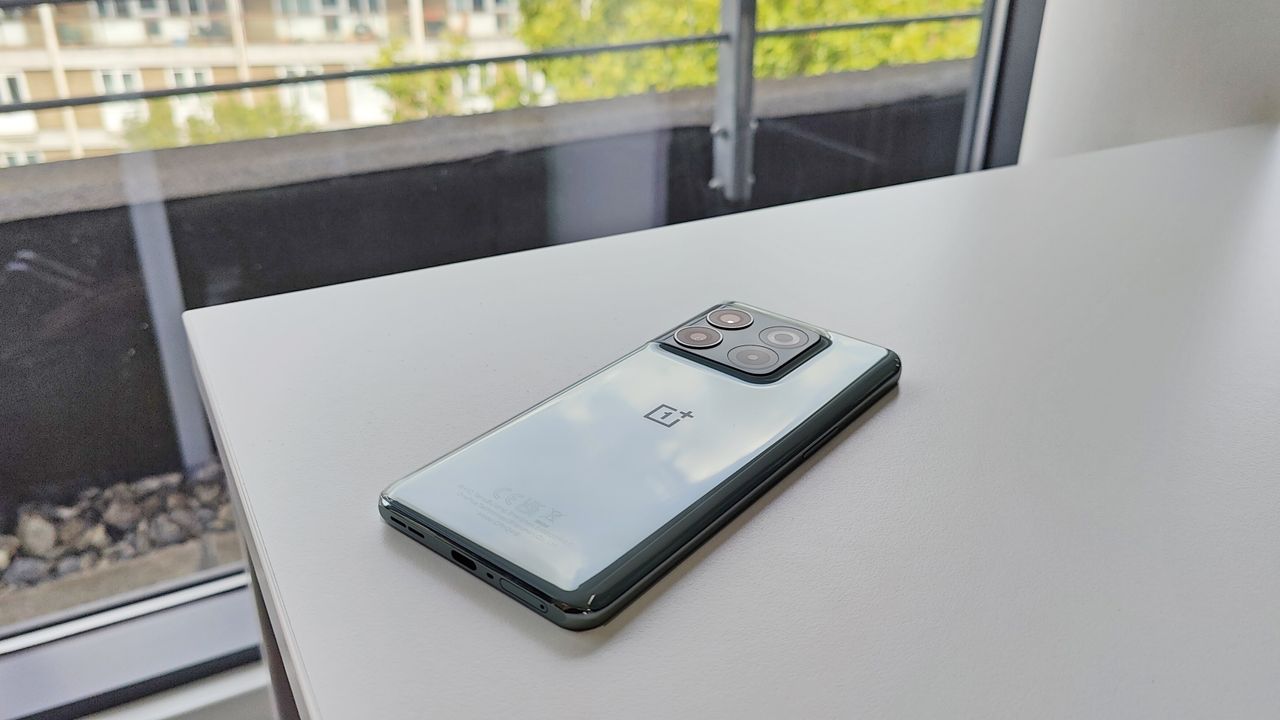 OnePlus 10T review: phone lying on a white desk with trees and building behind