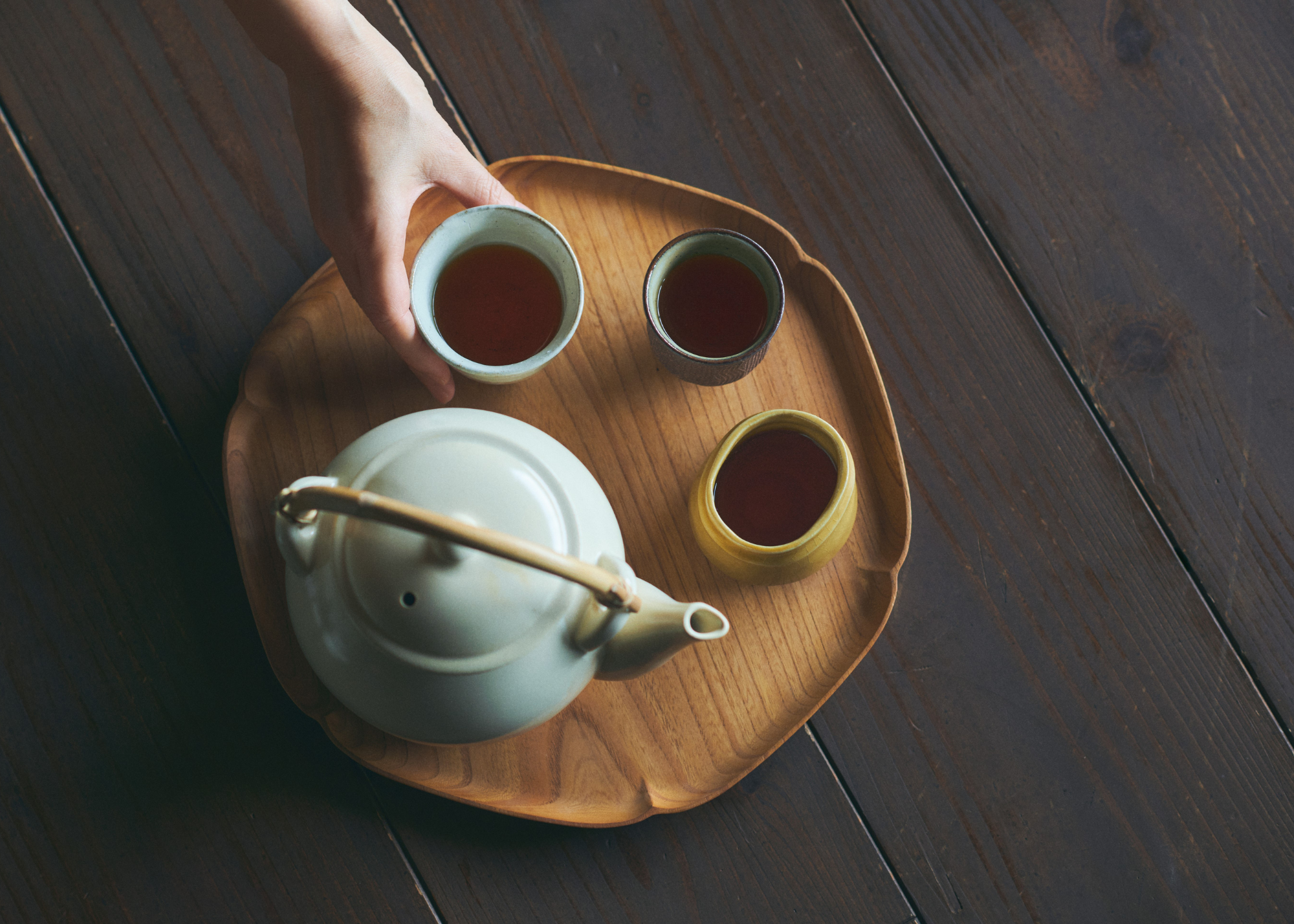 A table with a tray holding a teapot and three teacups