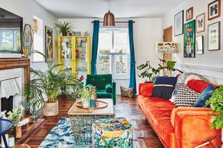 Living room with parquet floor, blue rug, orange sofa, blue armchair, yellow glazed cabinet and gallery wall