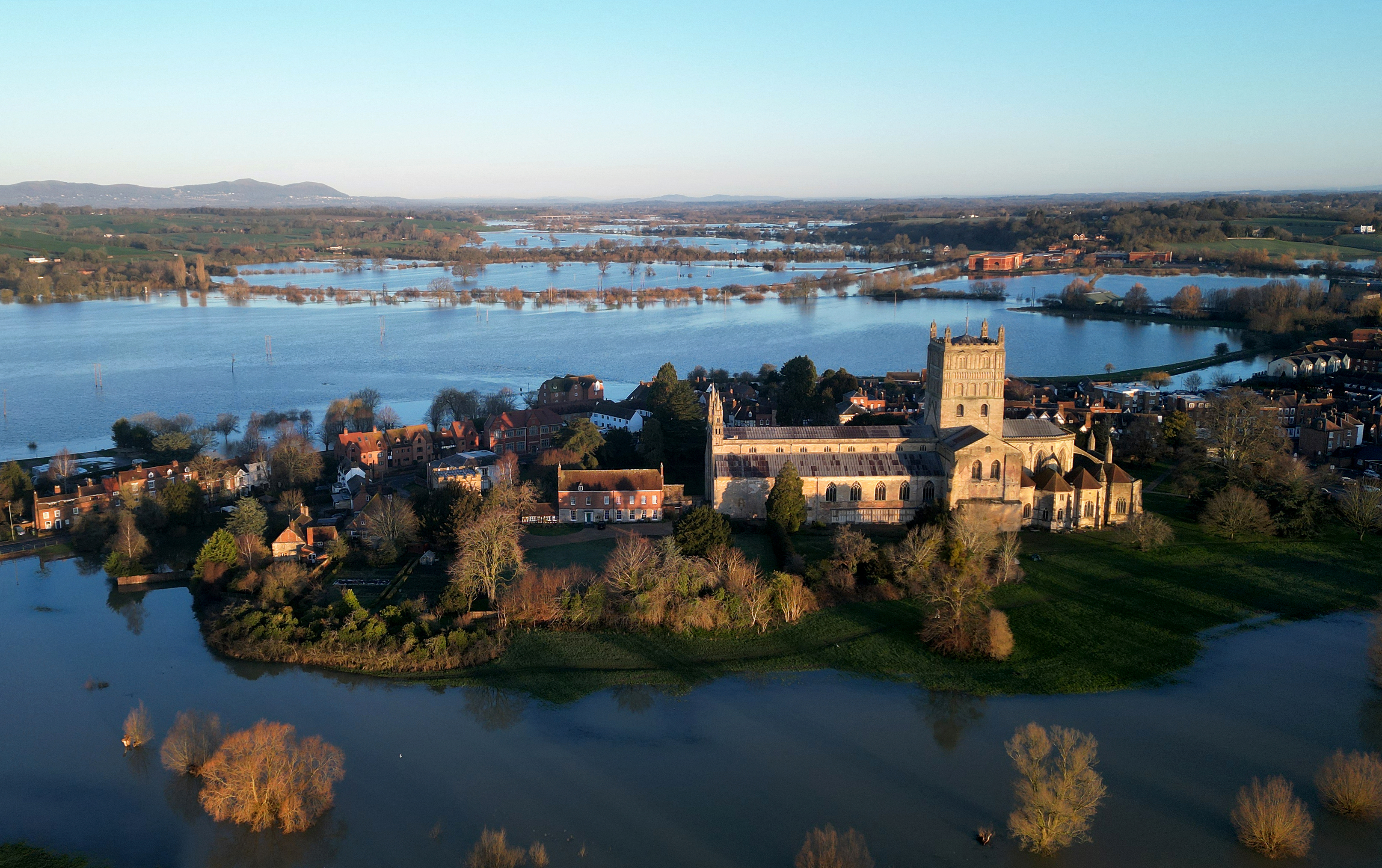 This aerial photograph taken on February 14, 2026 shows Tewkesbury Abbey on higher ground surrounded by floodwater from the confluence of the River Avon and River Severn in Tewkesbury, south west England, following prolonged rain over the winter months. (Photo by Paul ELLIS / AFP)