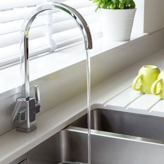 A kitchen sink with a running tap