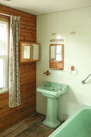 A dated bathroom with avocado sink and patterned curtains