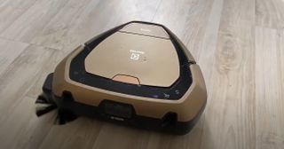 En svart och ljusbrun Robotdammsugare Electrolux Pure i9.2 står på ett träfärgat golv.