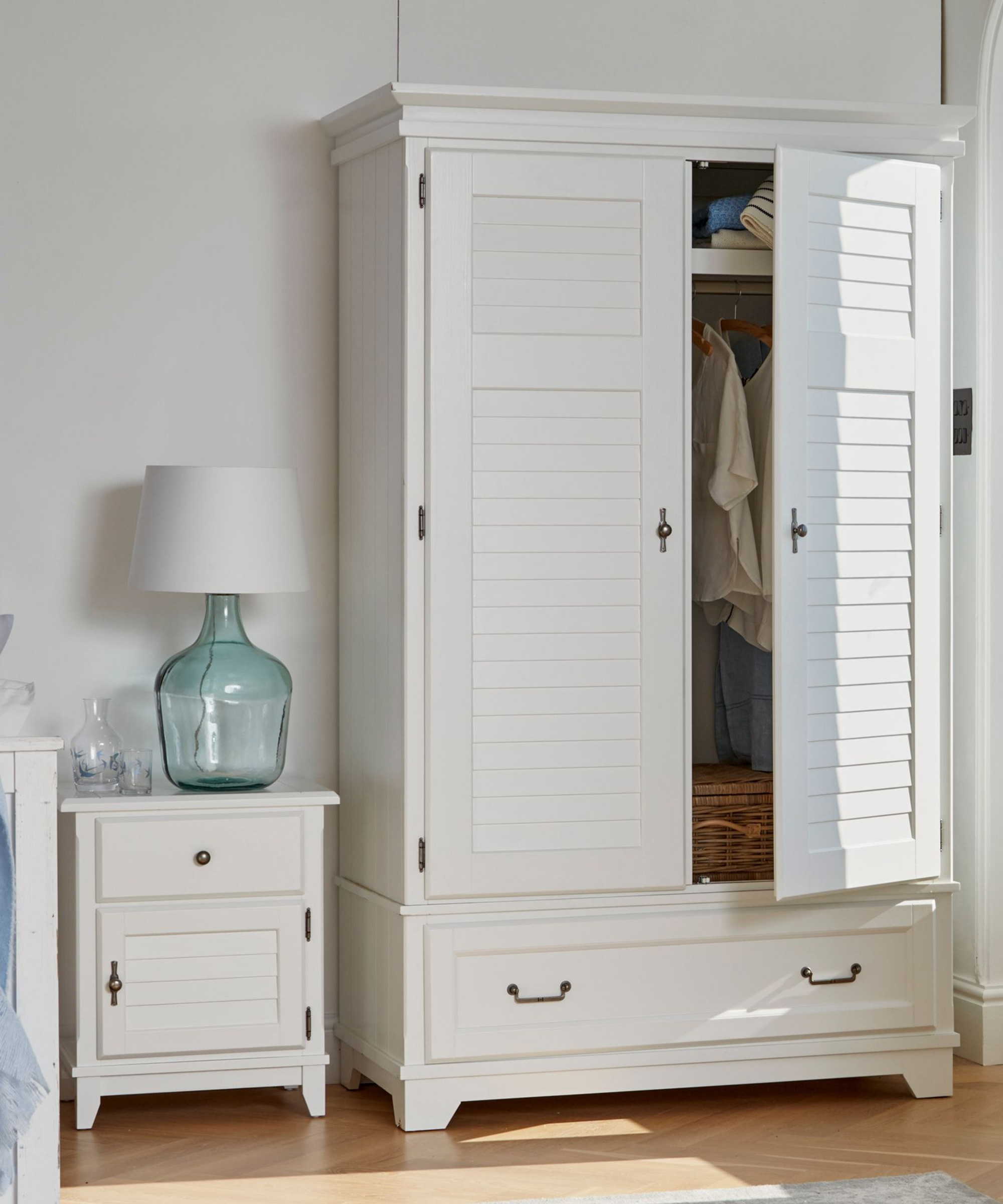 A white wardrobe with louvered doors and accompanying side board by Laura Ashley