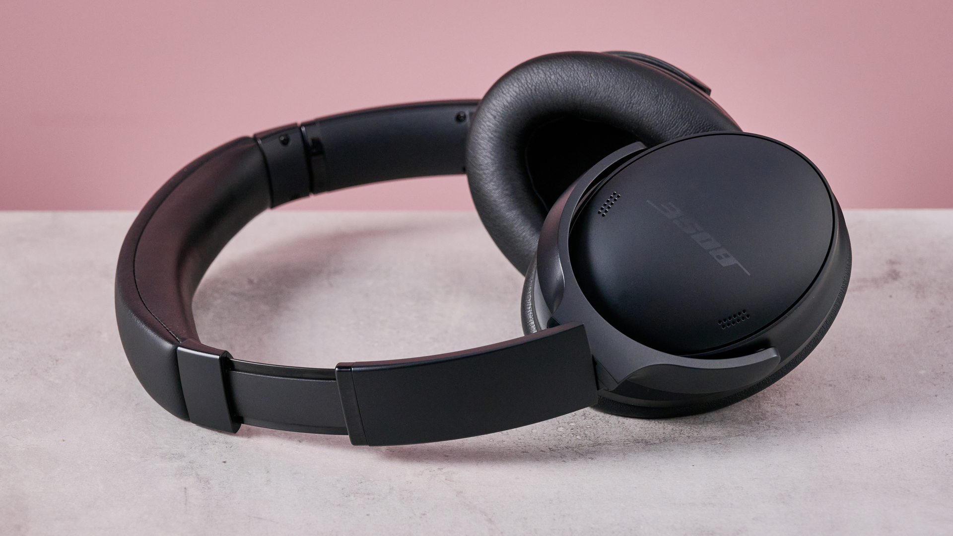 Bose QuietComfort Headphones on a gray surface with a pink background