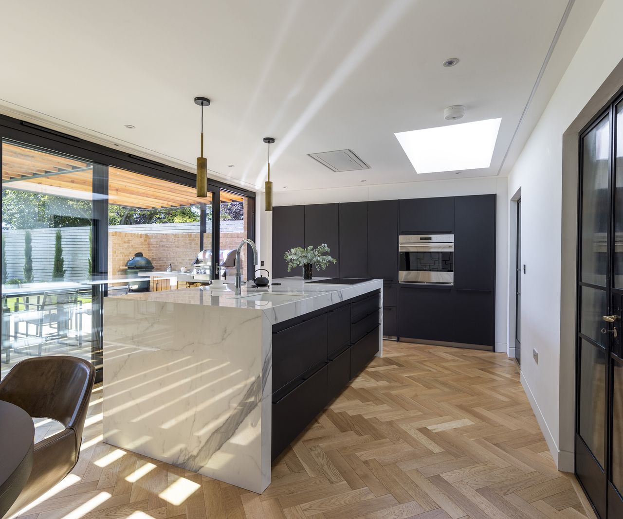 A modern kitchen renovation with dark cabinets and wood parquet flooring