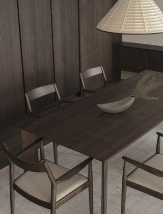 Dining table and chairs in dark wood with white lamp above it