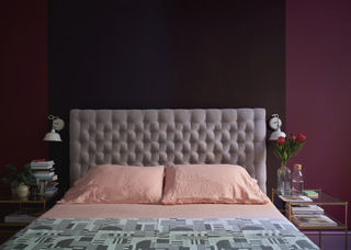 A bedroom with purple walls and light pink sheets