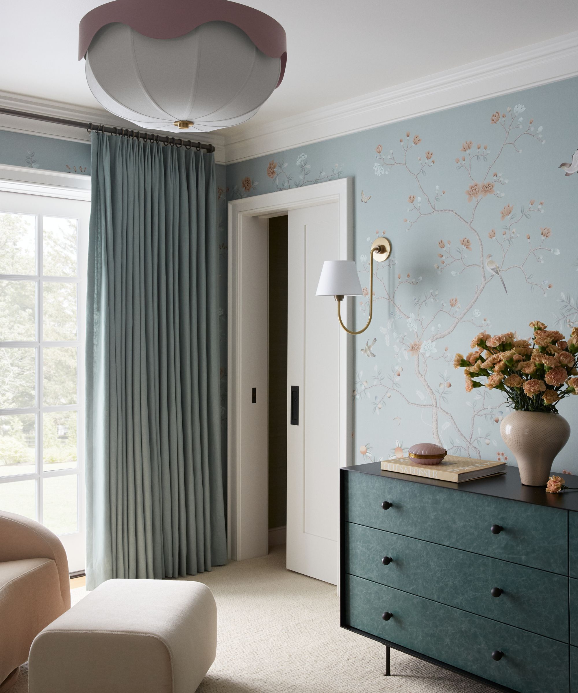 bedroom corner with blue floral wallpaper, blue drawers and long blue drapes