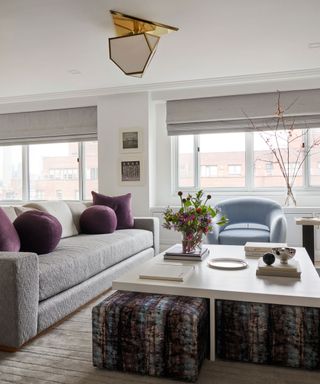 neutral living room with pops of purple and patterned pouffes