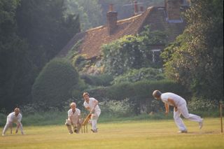 Men playing village green cricket