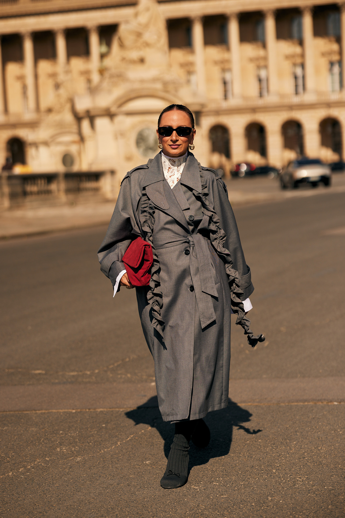 A street styler in Paris, France, styles a red trench with a gray jacket.