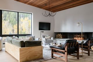 a modern living room with leather accent chairs and a wood framed sofa