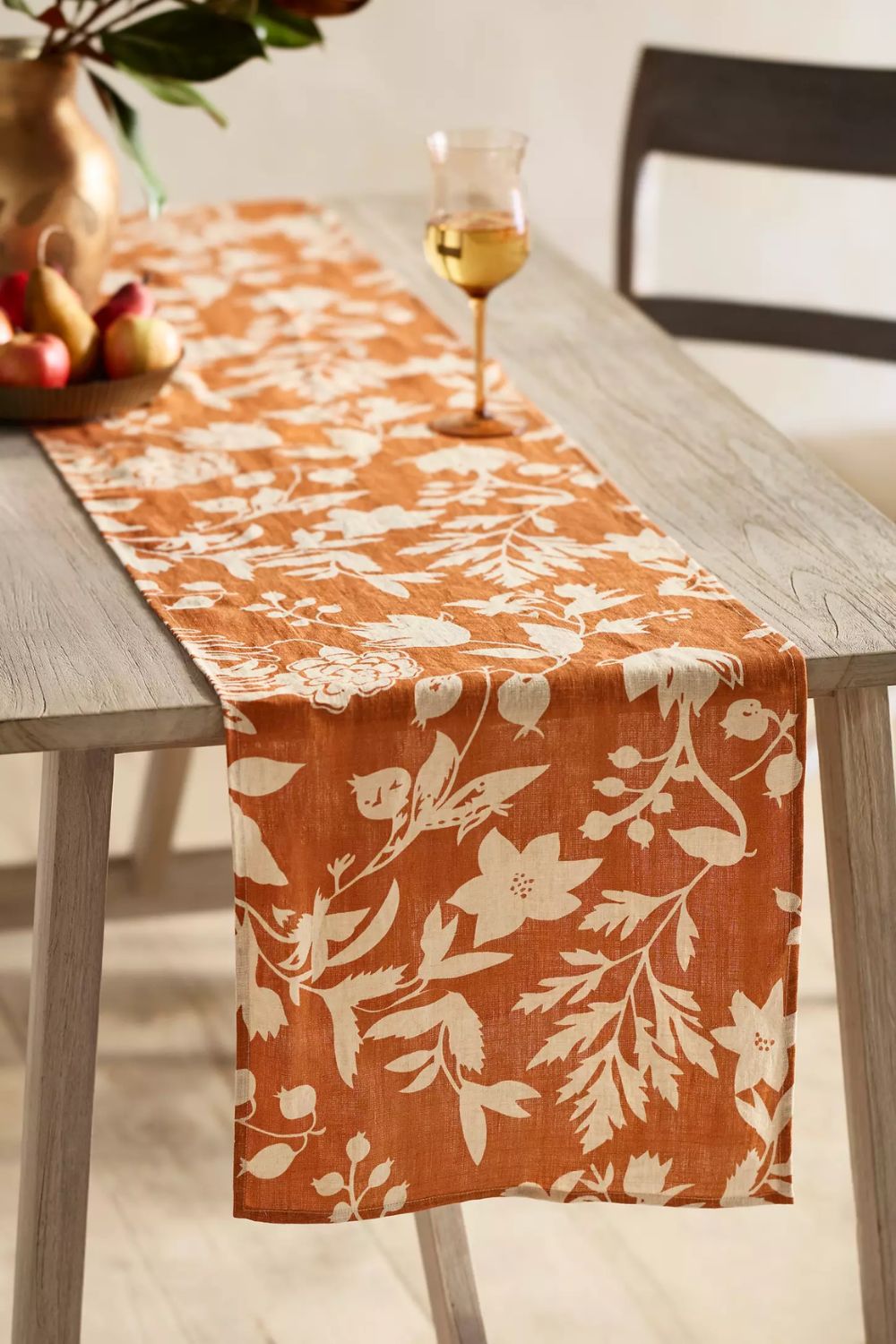 Orange linen table runner with white botanical motifs