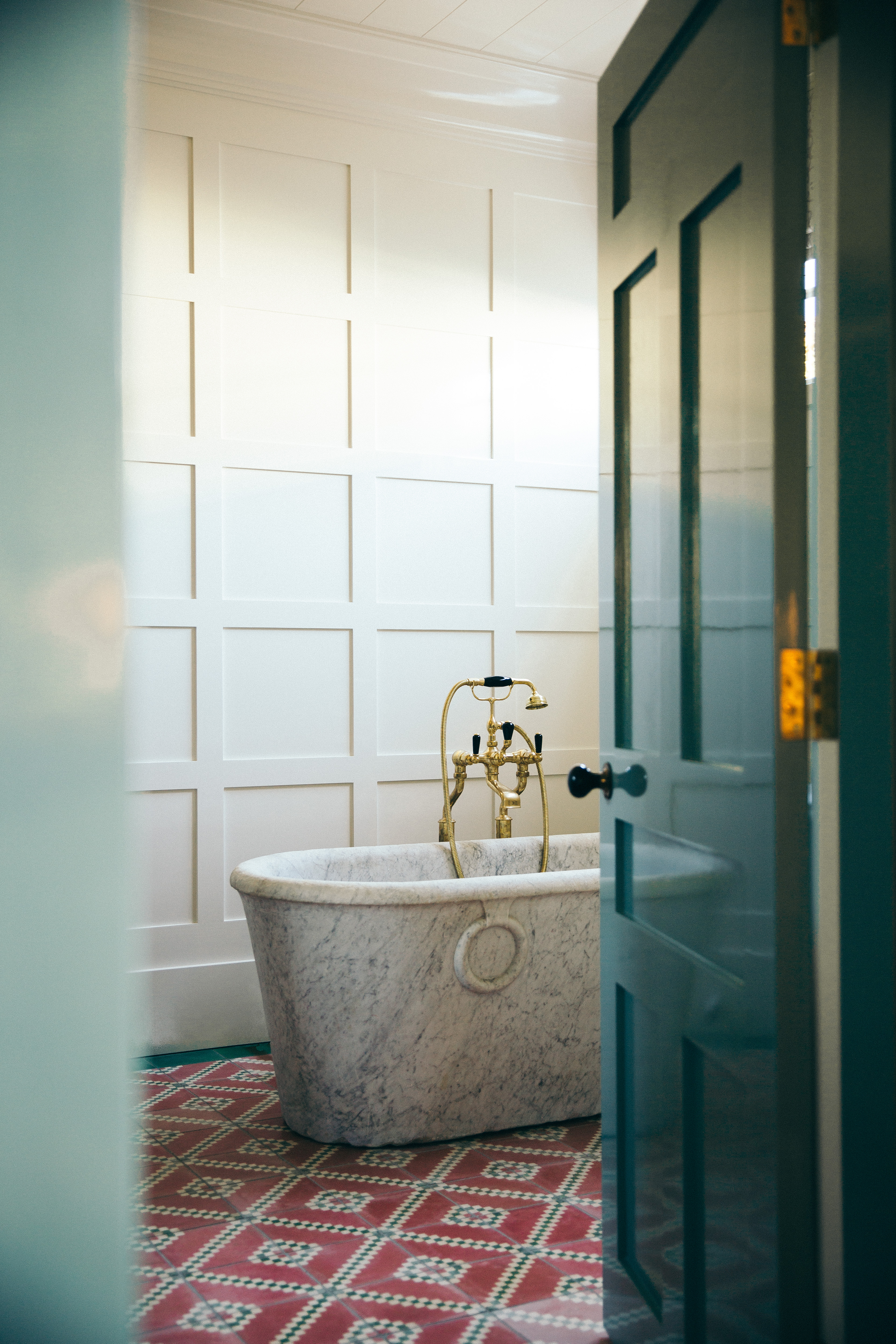 A bathroom with red patterned, antique tiles
