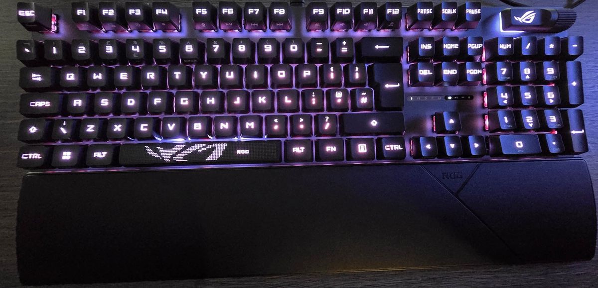 The Asus ROG Strix Scope II RX gaming keyboard photographed on a wooden desk.