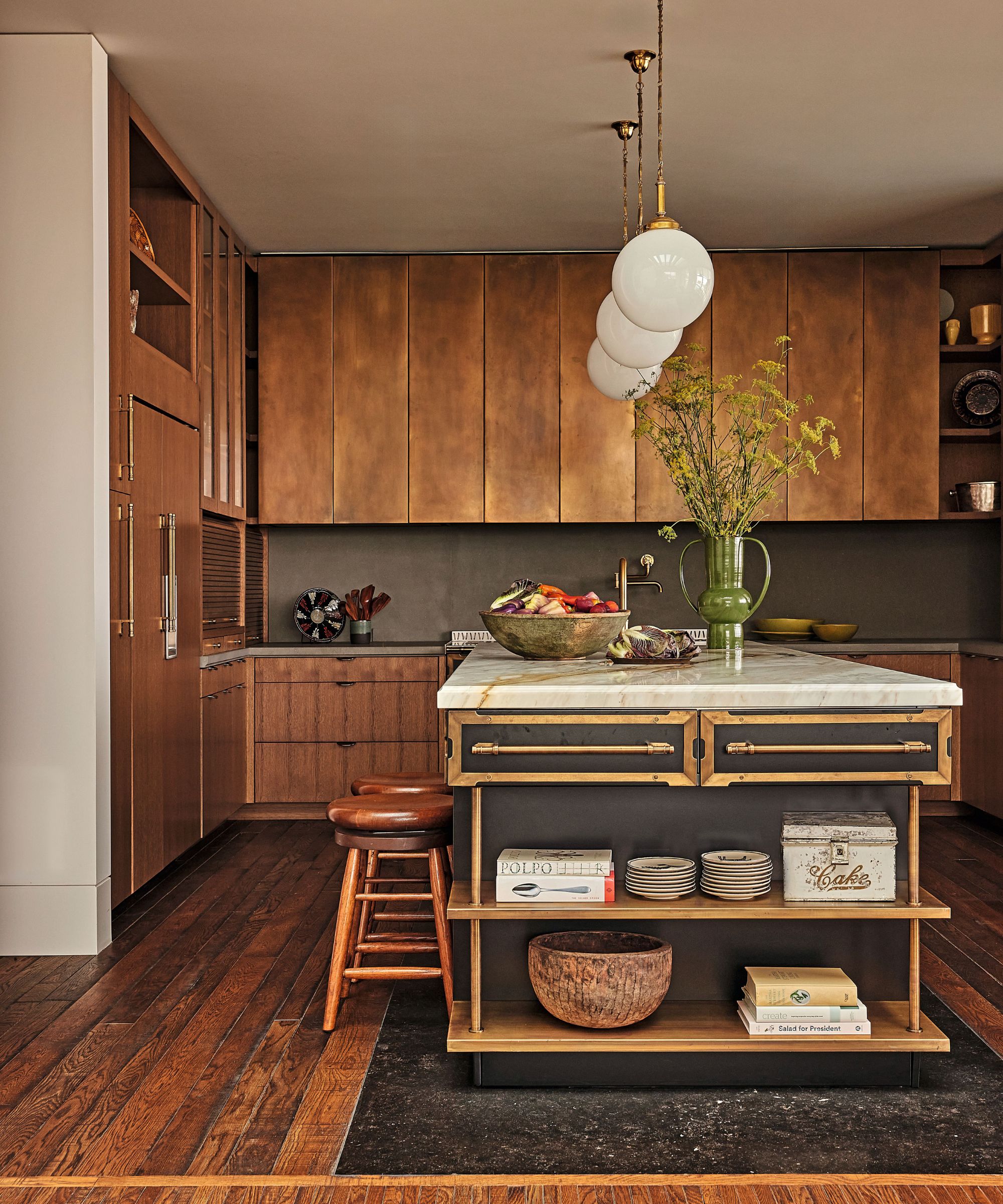 Warm wood kitchen featuring custom flat-panel cabinetry, globe pendant lights, and a marble-topped island with open display shelving