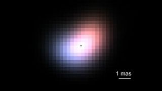 A blurry photo of red and blue light in the disk surrounding a star against a black background