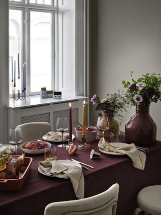 A Christmas table with grey napkins and yellow and red candles