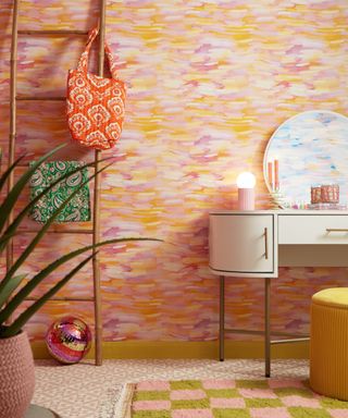 A small bathroom with pink and yellow painted walls, a wooden ladder and white curved vanity unit, pink patterned tiles and a pink and green checkered rug