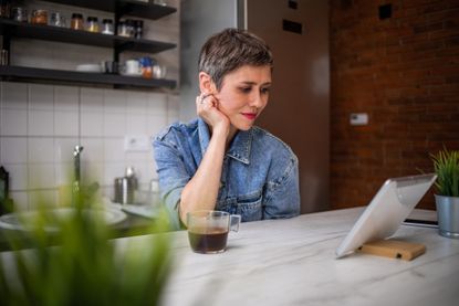 A woman checks her 401(k) on a tablet, with a concerned look on her face.