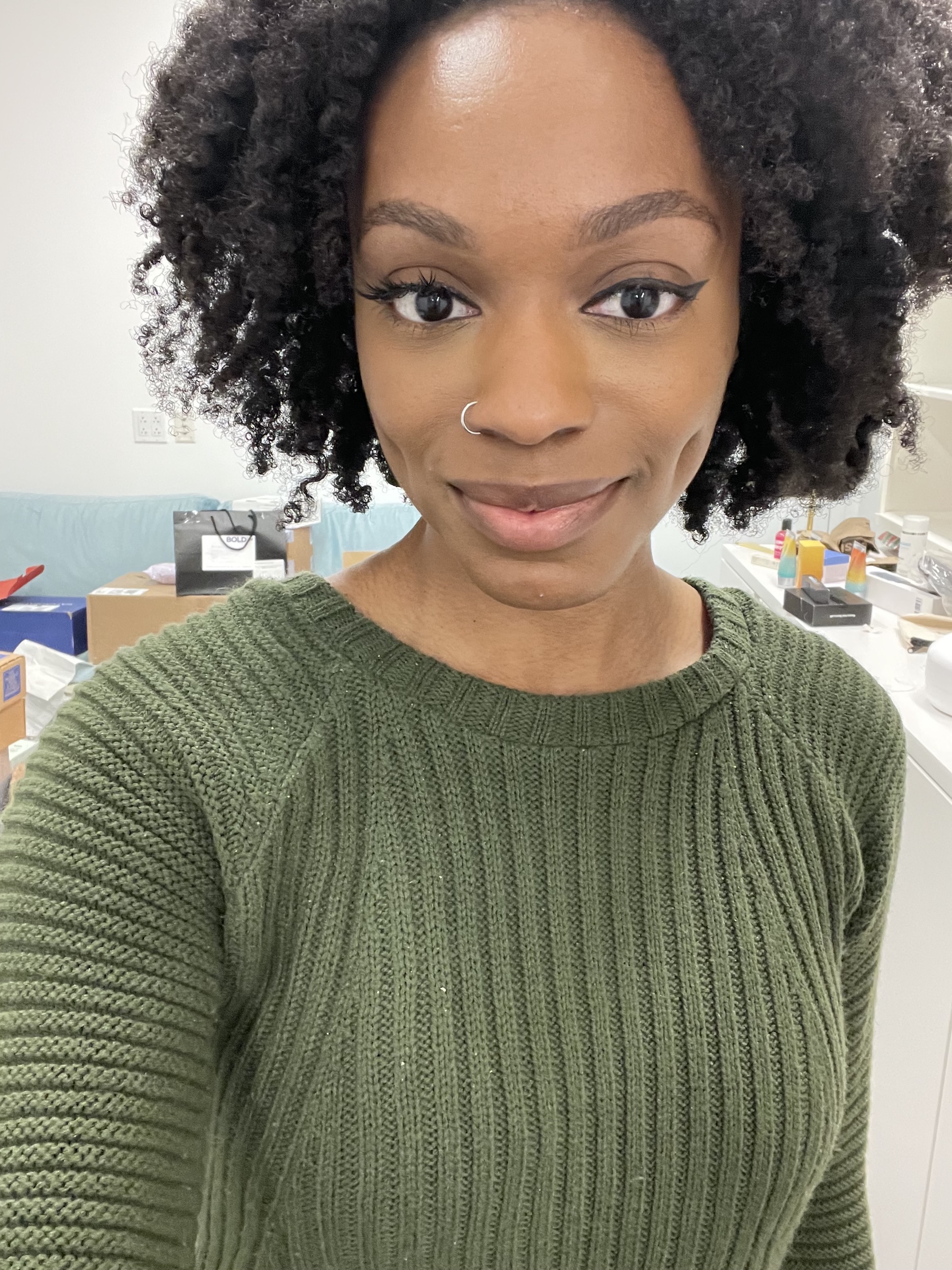 a selfie of a black woman with curly hair wearing a green sweater