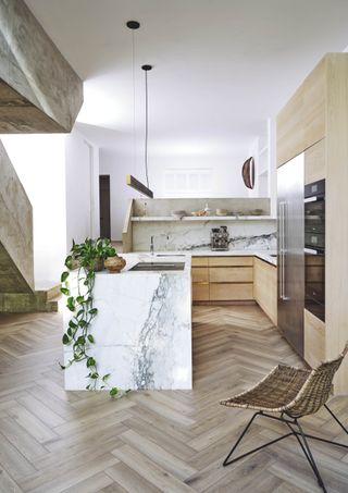 wooden kitchen with marble worktop and wooden herringbone floors