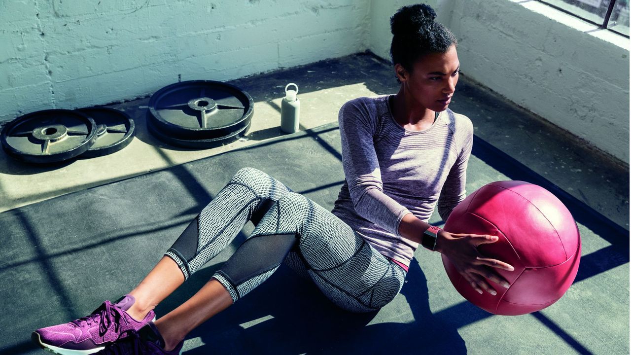 Fit young woman doing ab workout with medicine ball