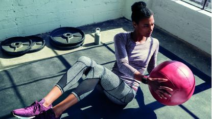 Fit young woman doing ab workout with medicine ball
