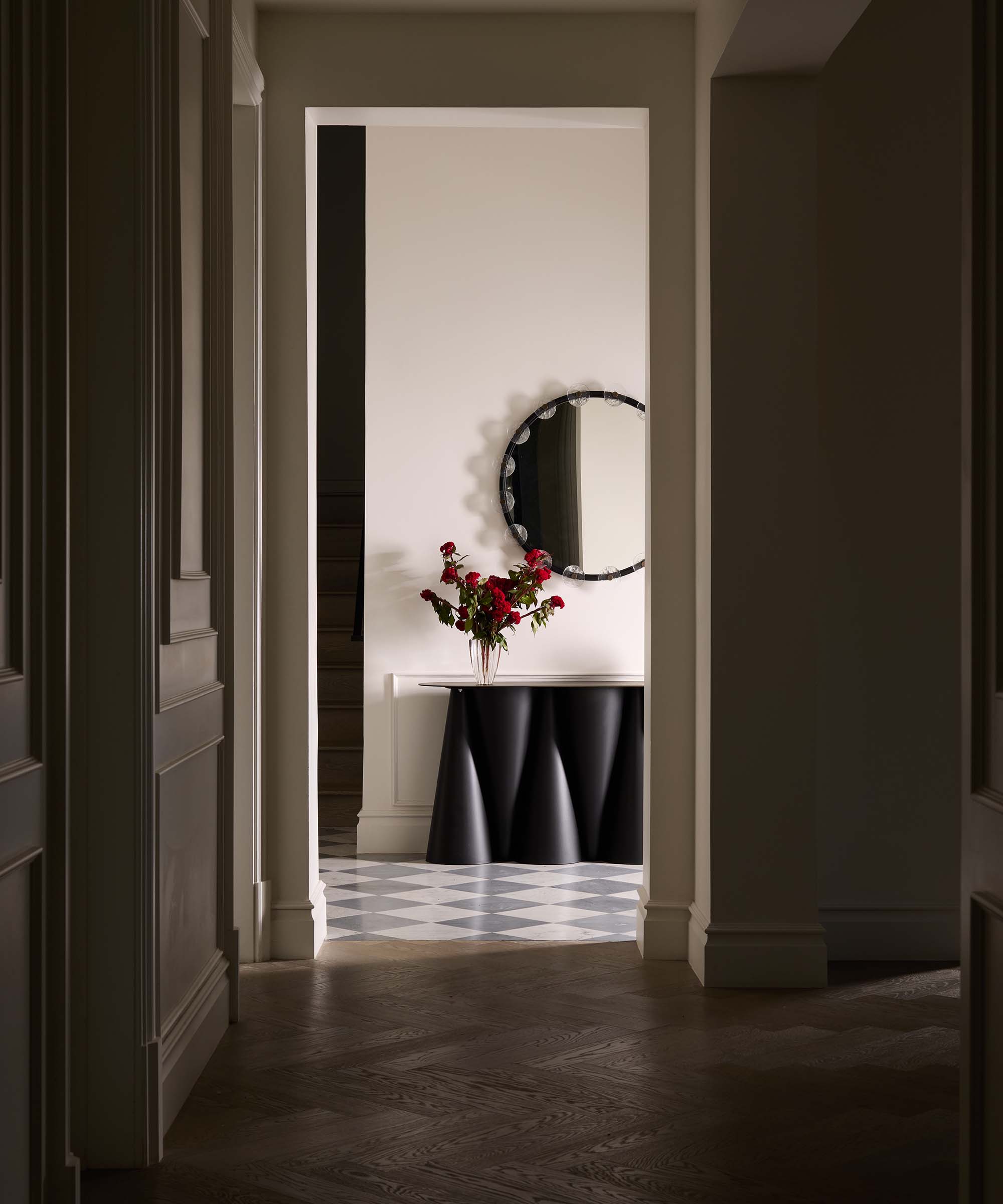 entryway with modern black console and large round mirror on the wall
