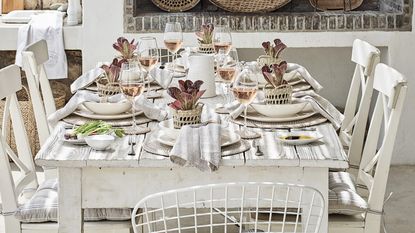 White dinnerware set displayed on top of round rattan placemat on dining table