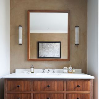 Brown bathroom wall with wooden mirror