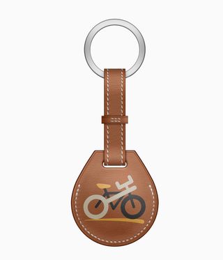 Tan leather Apple and Hermès AirTag with bicycle motif, against a white background
