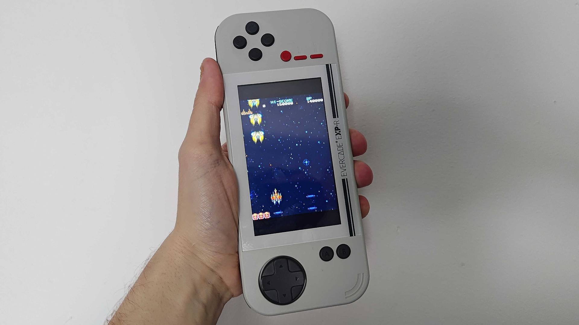 Evercade EXP-R in grey and red running in TATE mode with Truxton 2 gameplay on screen.
