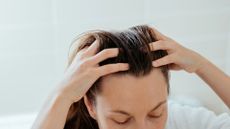 Woman running fingers through long hair, wondering can HRT cause hair loss