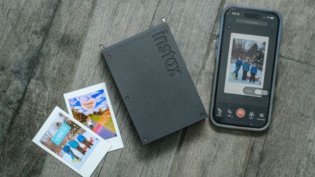 The Fujifilm Instax Mini Link+ printer with prints on a grey floor