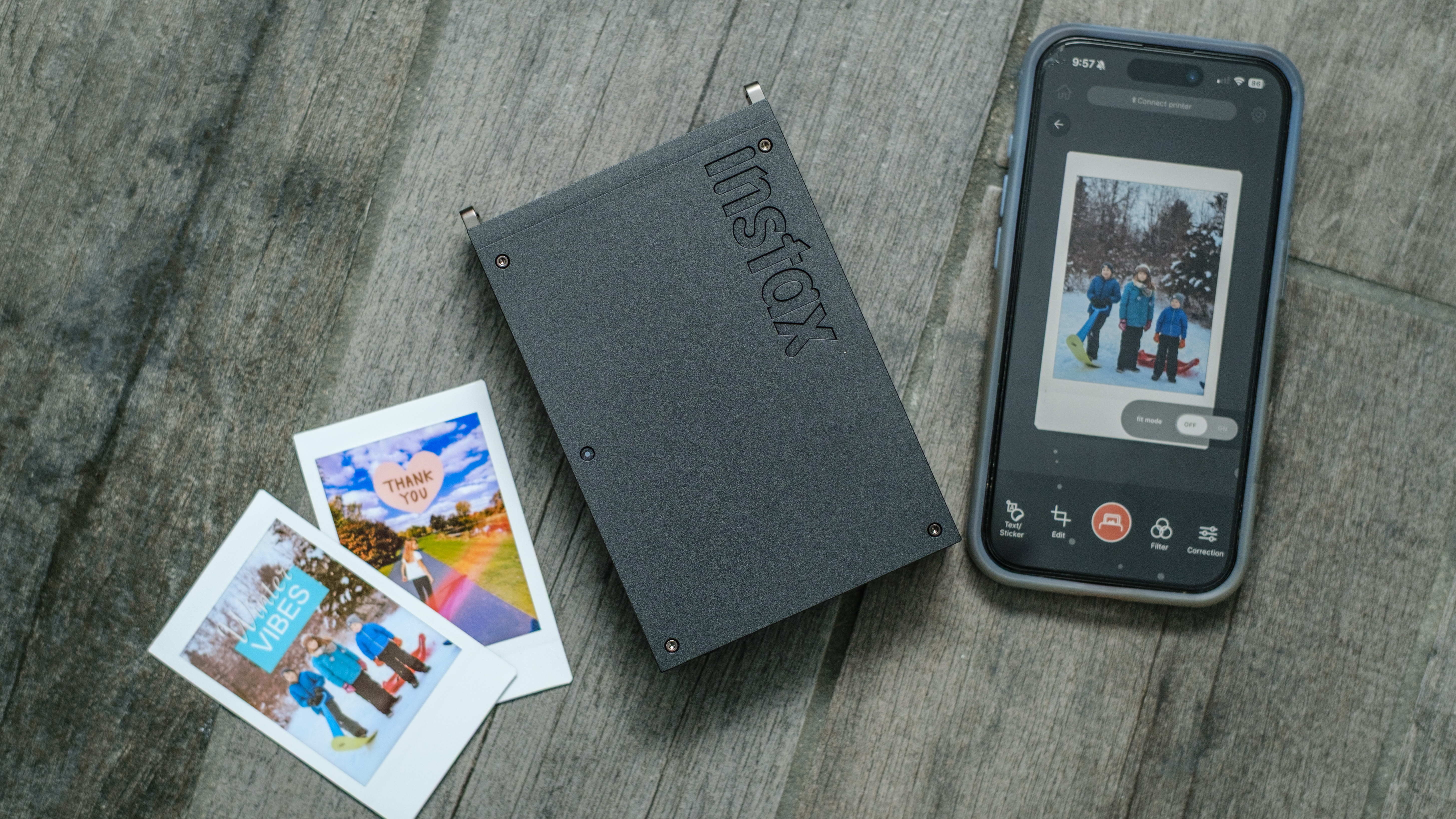 The Fujifilm Instax Mini Link+ printer with prints on a grey floor