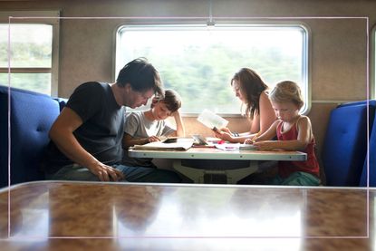 Family including two children entertained while sitting at a table on a train